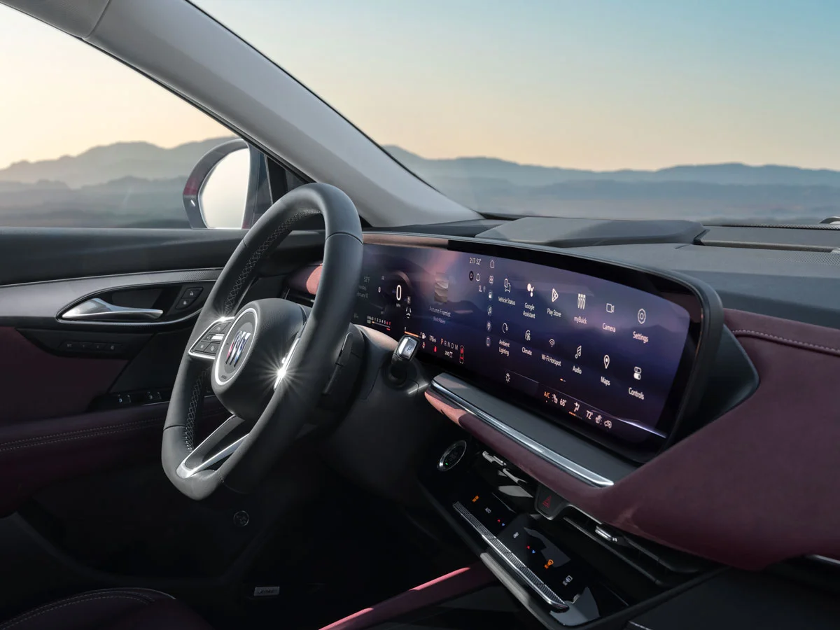 Interior of a modern car with a digital dashboard and large infotainment screen, overlooking a mountain landscape.