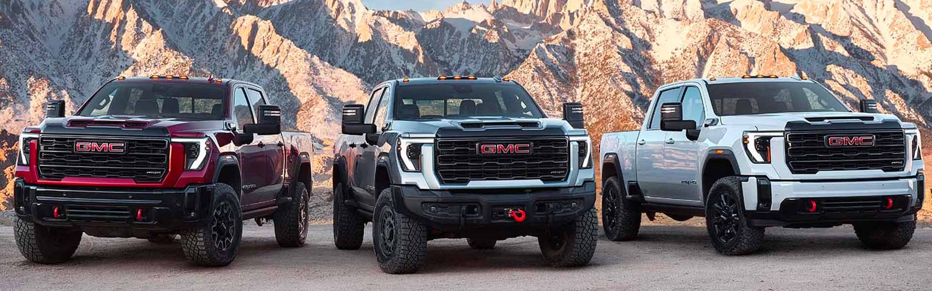Three GMC heavy-duty pickup trucks in mountains